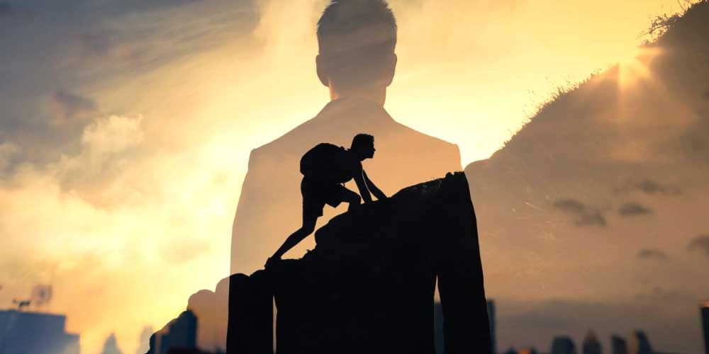 Uomo che scala una parete e poi in sovraimpressione stesso uomo in giacca e cravata. Sta a simboleggiare il volersi milgiorare sempre